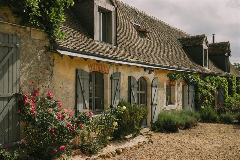 Une longère aux volets gris, des rosiers sous les fenêtres